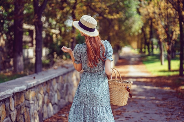 Indiase zomer achterkant van roodharige vrouw loopt in het park draagt in fladderende jurk kijkt zijwaarts