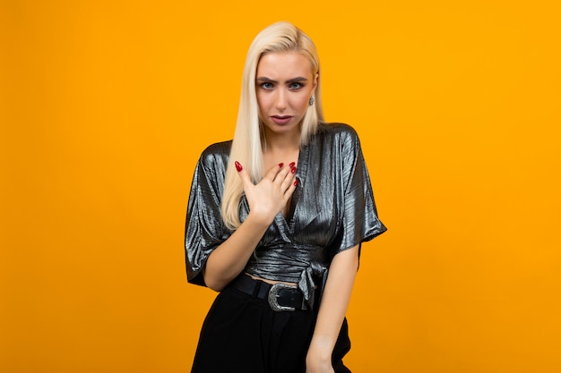 indignant emotional blond girl on a yellow wall  close-up