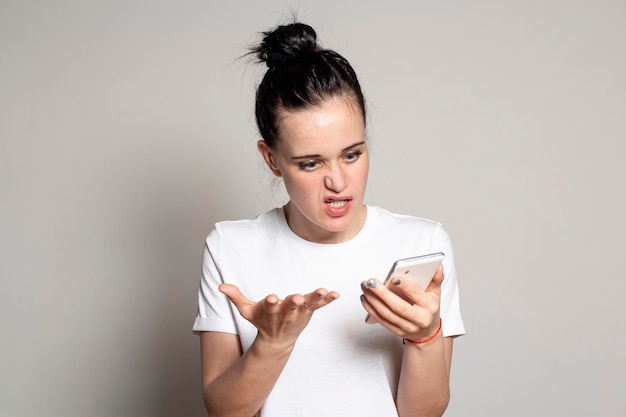 Indignation upset young woman looks at her smartphone sees bad news or photos gets angry