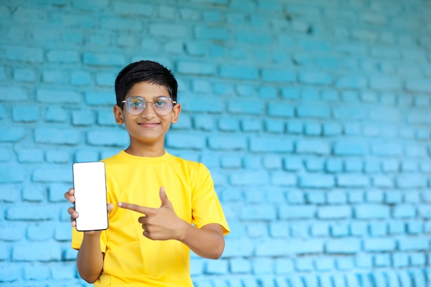 Indisch kind dat het smartphonescherm toont. online onderwijsconcept