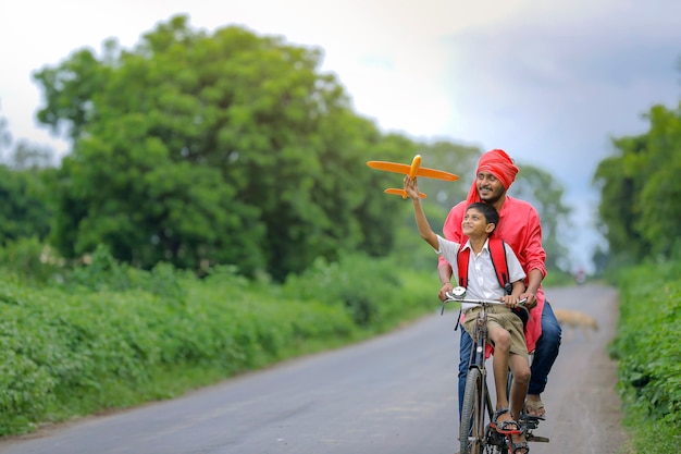 Indisch kind speelt met speelgoed vliegtuig met zijn vader op cyclus