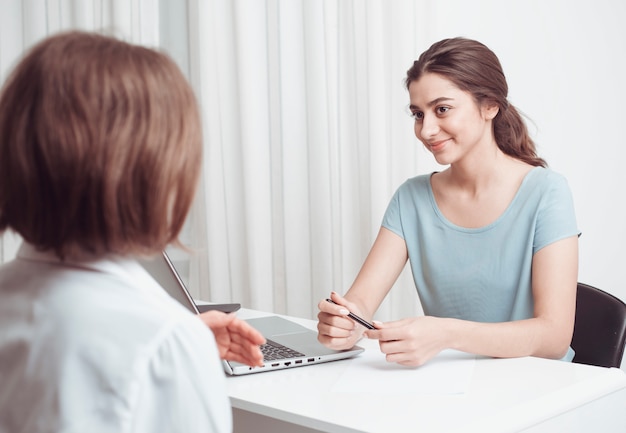 Indisch meisje adviseert een vrouw aan een vrouw. Vrouwen praten vriendelijk terwijl ze op kantoor zitten.