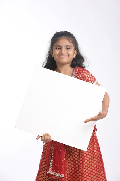 Indisch meisje dat wit bord met kopieerruimte toont