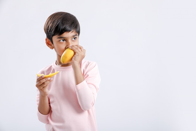 Indische / aziatische kleine jongen die mango eet