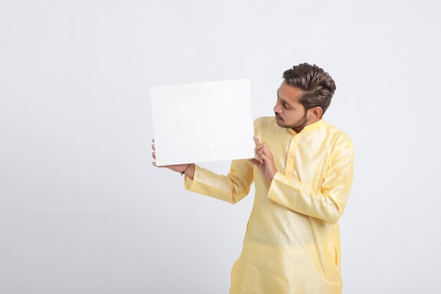 Indische mens die wit bord houdt dat zich over witte muur bevindt