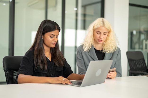 Indische student die laptop in bibliotheekruimte met vriend gebruikt