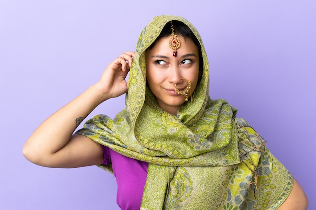 Indische vrouw die op purpere muur wordt geïsoleerd die twijfels heeft