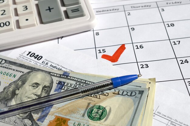 individual income tax return blank with dollar bills calculator and pen on calendar page with