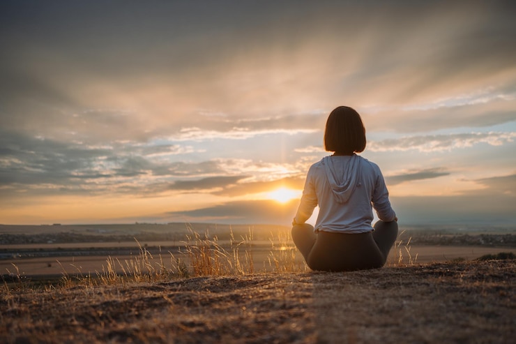 Photo an individual peacefully practices meditation on a hill during sunset blending with the serenity and