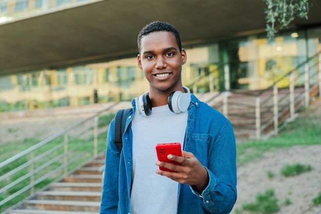 Individual portrait of one african american guy looking at camera and holding a smartphone real