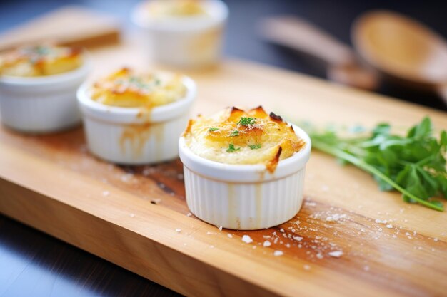 Individual ramekins of gratin dauphinois on a wooden board