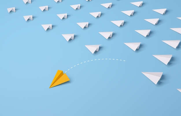 Individual and unique leader yellow paper airplane changing direction on blue background