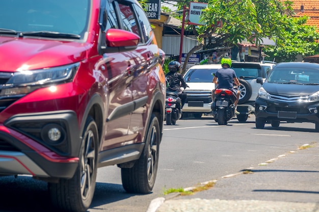 Indonesia. City street on the island of Bali. Sunny day. Cars and scooters