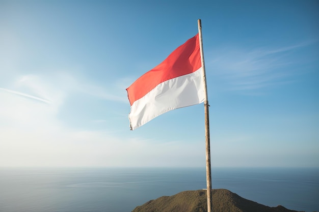 바다 배경의 푸른 하늘에 펄럭이는 인도네시아 국기 빨간색과 흰색 깃발