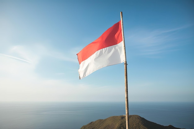 Indonesia national flag waving in the blue sky on the ocean background Red and white flag