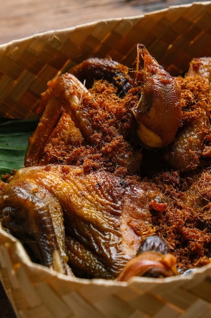 인도네시아 전통 요리. 나무 테이블 위에 짠 대나무 상자에 담긴 아얌 고렝 칼라산