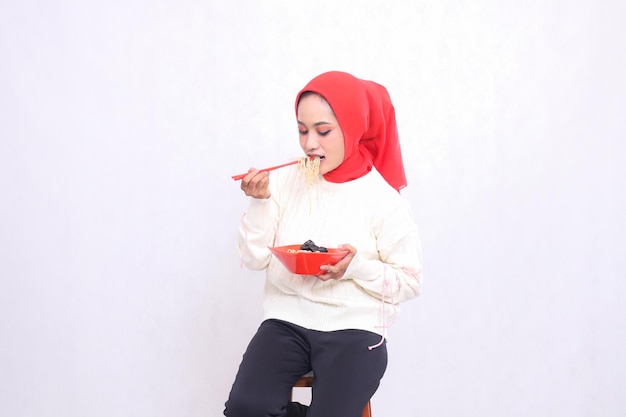 indonesia woman in hijab bites noodles with chopsticks ampbowl contains ramen Chinese food Beautifu