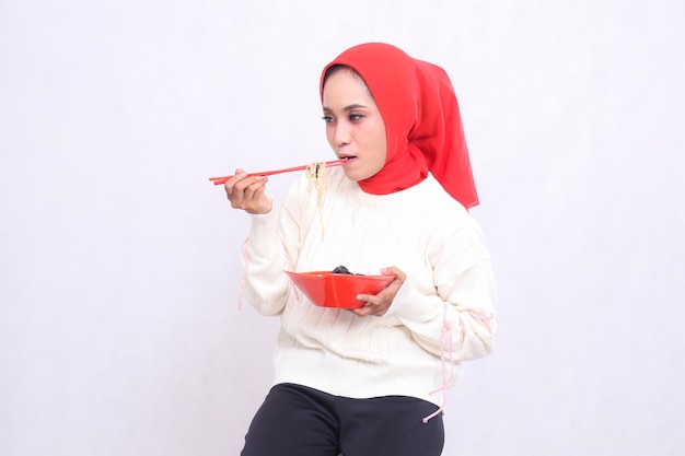 indonesia woman wearing a hijab candidly eats noodles with chopsticks and a bowl of ramen Chinese