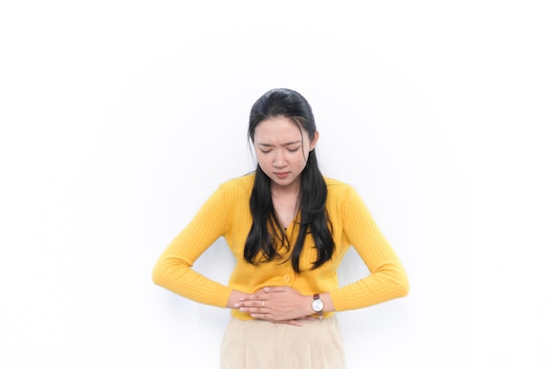 Indonesian Asian woman in yellow dress having stomach ache