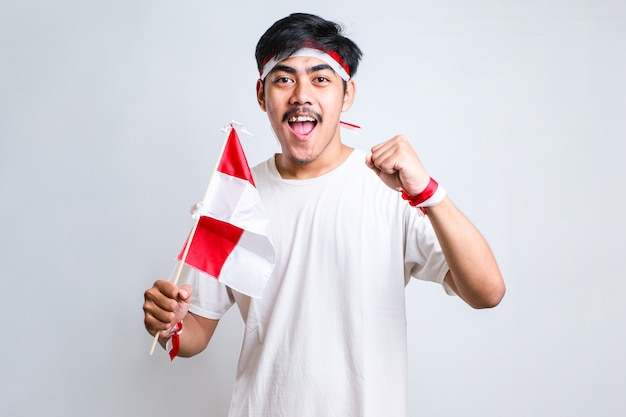 Indonesian boy doing victory and winning gesture, wearing red and white headband over white background