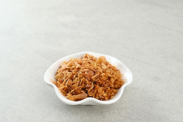 Indonesian crispy deep fried shallots or onion flakes bawang goreng in small bowl Selected focus