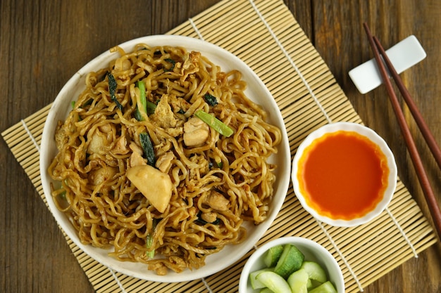 Indonesian fried noodles served with acar timun on the white plate and wooden background