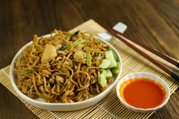 Indonesian fried noodles served with acar timun on the white plate and wooden background