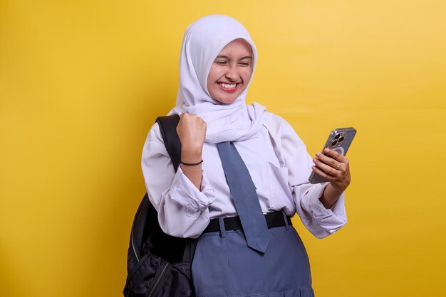 Indonesian high school student holding a mobile phone while clenching fist celebrating success