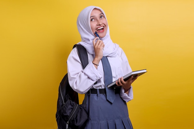 Indonesian high school student in white and grey uniform thinking and smiling while looking up