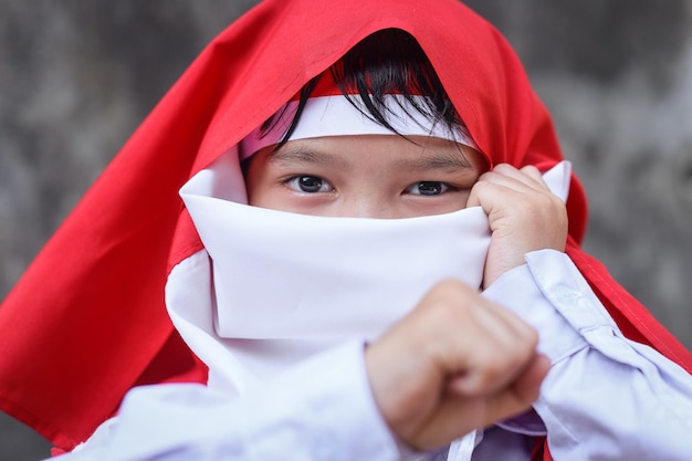 Foto i bambini indonesiani affrontano il viso coperto dalla bandiera indonesiana da vicino