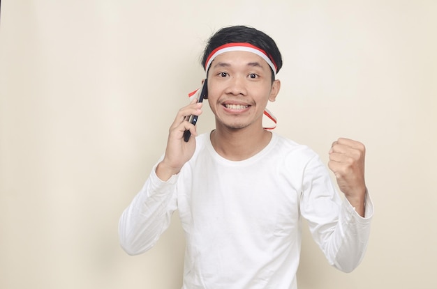 Uomo indonesiano che sorride mentre tiene un telefono cellulare durante la celebrazione del giorno dell'indipendenza