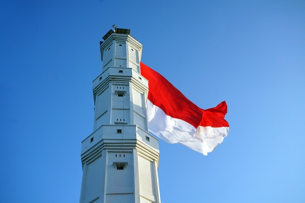 Photo indonesian national flag on lighthouse with blue sky background