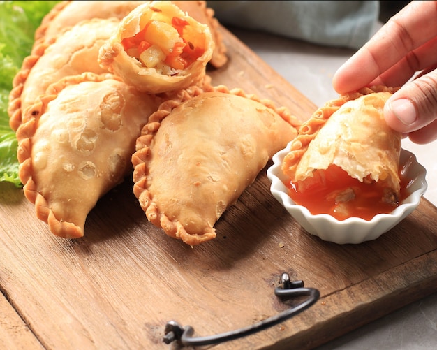 Torta pastello indonesiana servita su un piatto bianco accompagnata da tè. popolare come curry puff (karipap) o jalangkote makasar.. mangiare con salsa piccante sambal