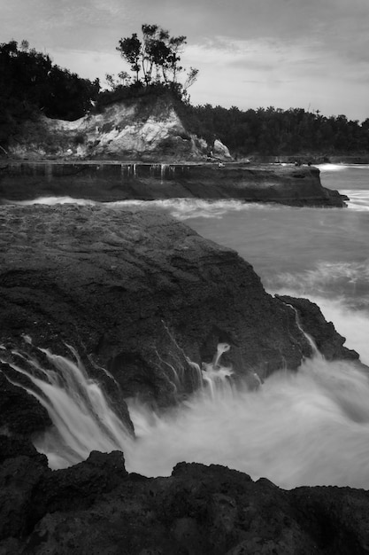 Foto in bianco e nero di paesaggi indonesiani di scogliere sulla spiaggia e bellissime onde