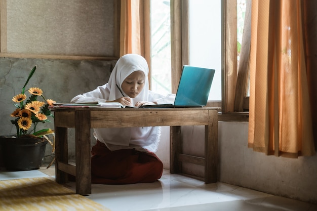 写真 自宅でオンラインレッスン中に宿題を勉強しているインドネシアの女子高生