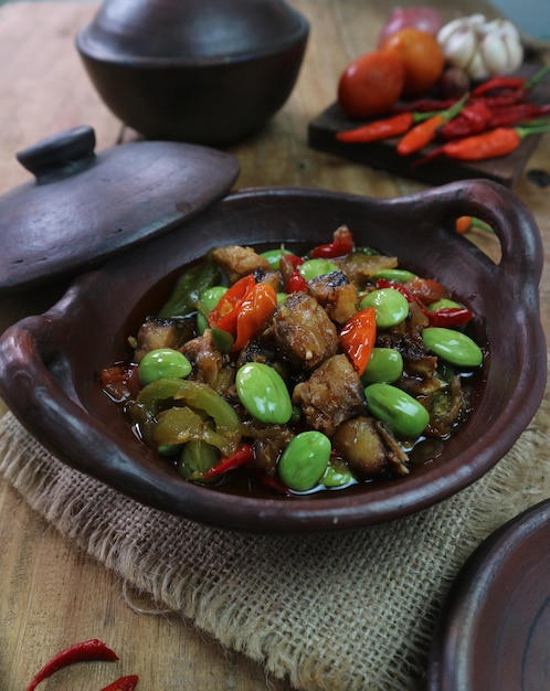 Foto petai saltato in padella speziato indonesiano servito in un wok di argilla