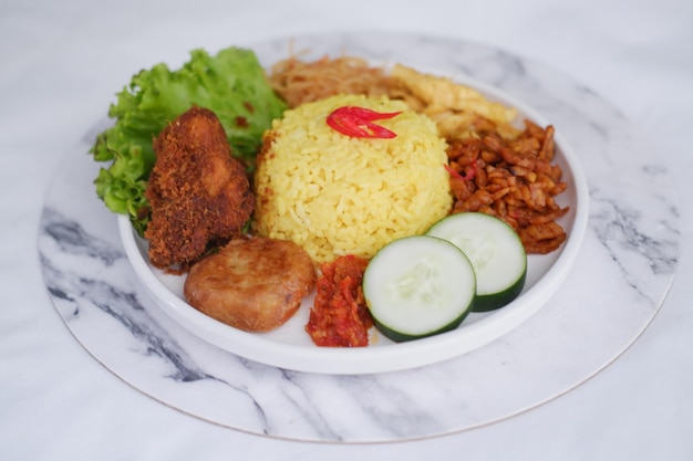 indonesian style yellow rice with chicken and side dishes in white plate