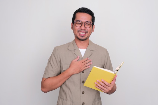 Indonesian teacher smiling happy while holding a book