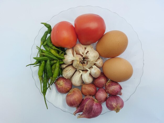 Foto cucina tradizionale indonesiana spezie pomodori cipolle peperoncini vista dall'alto isolati su bianco