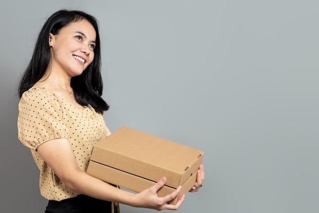 Indonesian woman posing holding a pizza box while looking up