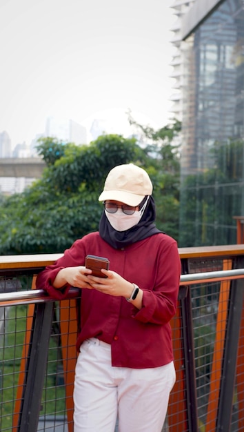 Indonesian woman wearing red and white clothes while replying to messages on her cellphone