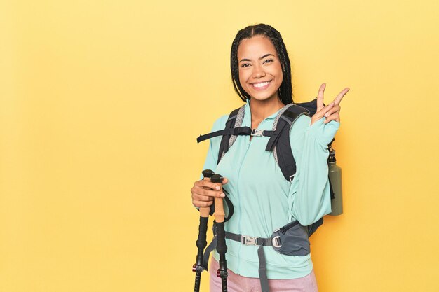 Photo indonesian woman with hiking gear on yellow showing number two with fingers