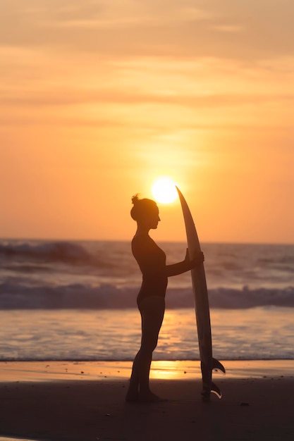 Indonesië, Bali, jonge vrouw met surfplank bij zonsondergang