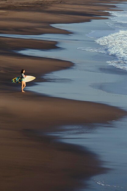 Indonesië, Bali, jonge vrouw met surfplank