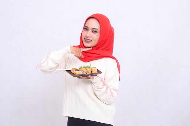 Indonesië meisje in hijab gelukkig gebaren naar links amp brengt een bord met sushi Japanse
