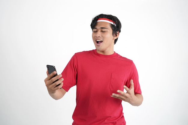 Indonesië Onafhankelijkheidsdag Concept. Indonesische man kijkt naar mobiele telefoon met verrassingsuitdrukking