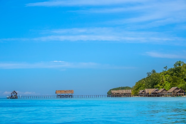 Indonesië. Tropisch eiland in de vroege avond. Meerdere hutten op palen in het water en een lange houten steiger