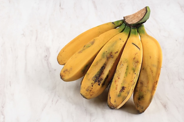 Indonesische Fruit: Pisang Kepok Kuning (Musa acuminata), gele lokale banaan geïsoleerd op witte marmeren tafel. Bovenaanzicht met kopieerruimte voor tekst