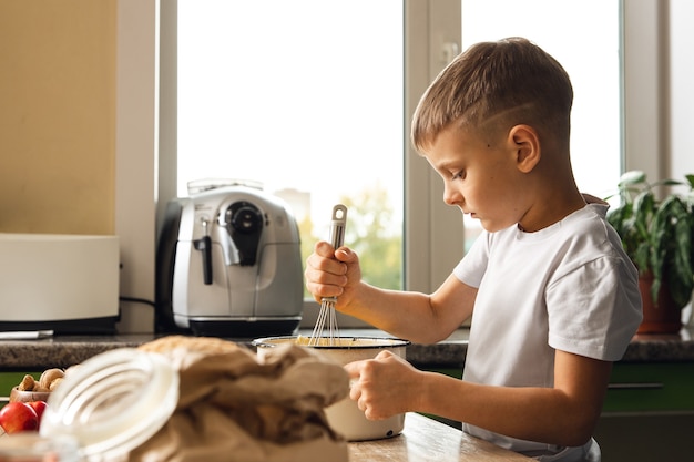 Indoor activiteit. Jong kindjongen die in de keuken koken. Taarten of koekjes maken