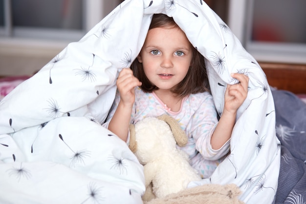 Indoor shot of charming little girl with big eyes